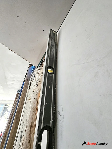 Checking the wall with a spirit level before glue plasterboard on